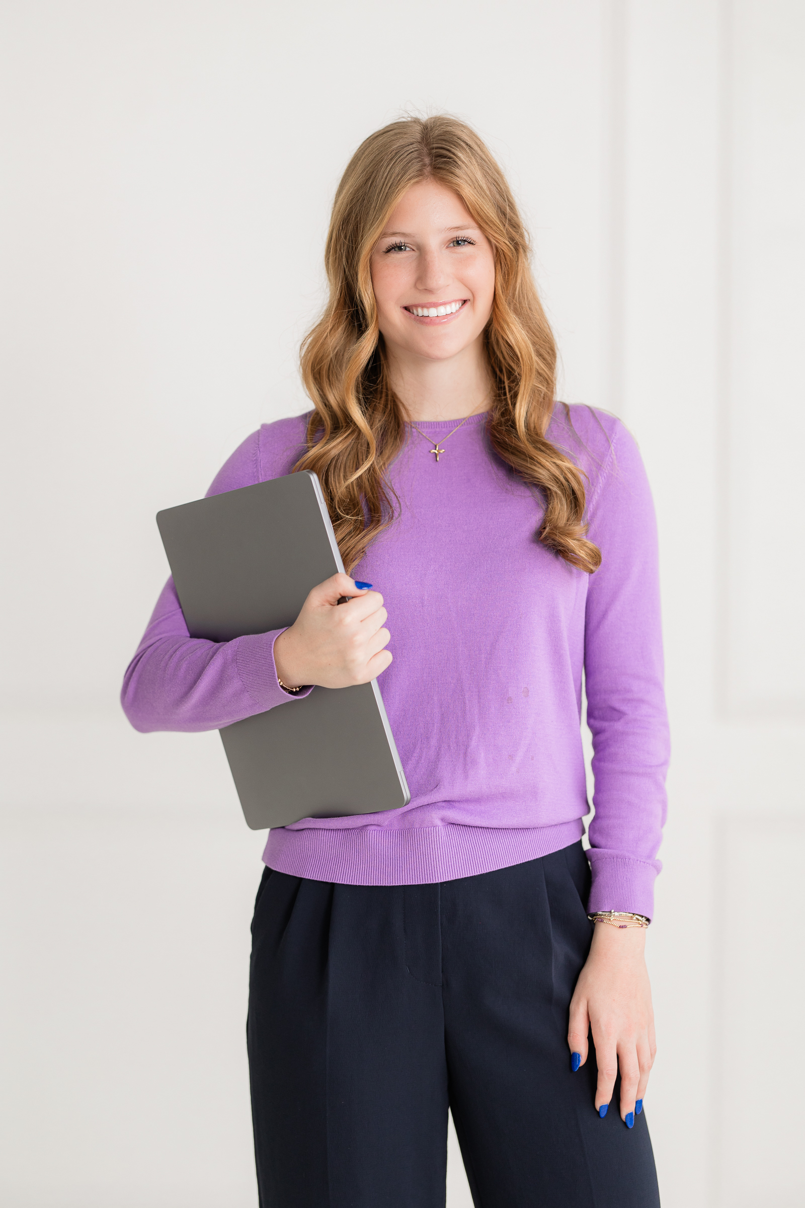modern branding photo of a marketing and analytics student holding a laptop in a clean studio setting
