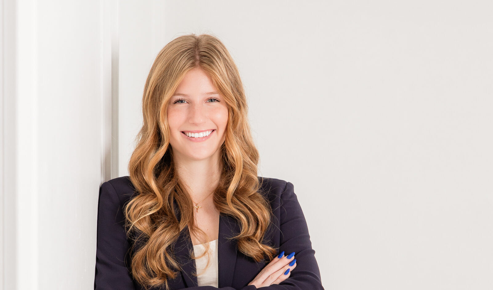 What do your branding photos in Atlanta say confident personal brand headshot leaning against a white wall in a professional outfit