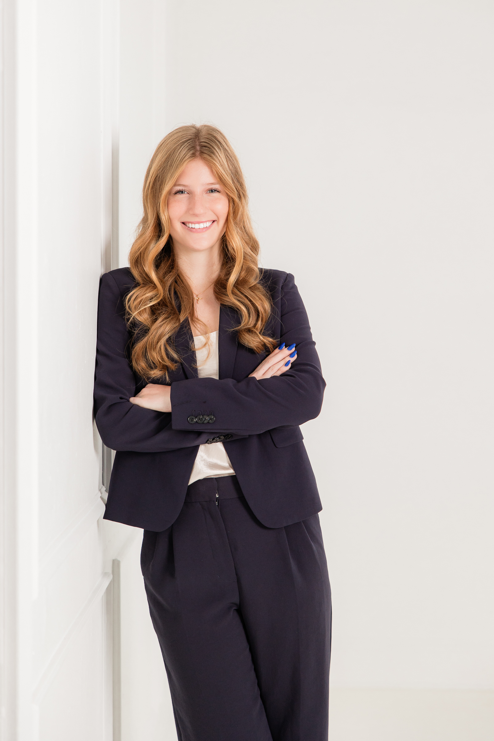 Professional branding headshot of young woman in navy suit standing confidently in a bright studio, showing what does your branding photos in Atlanta say about you