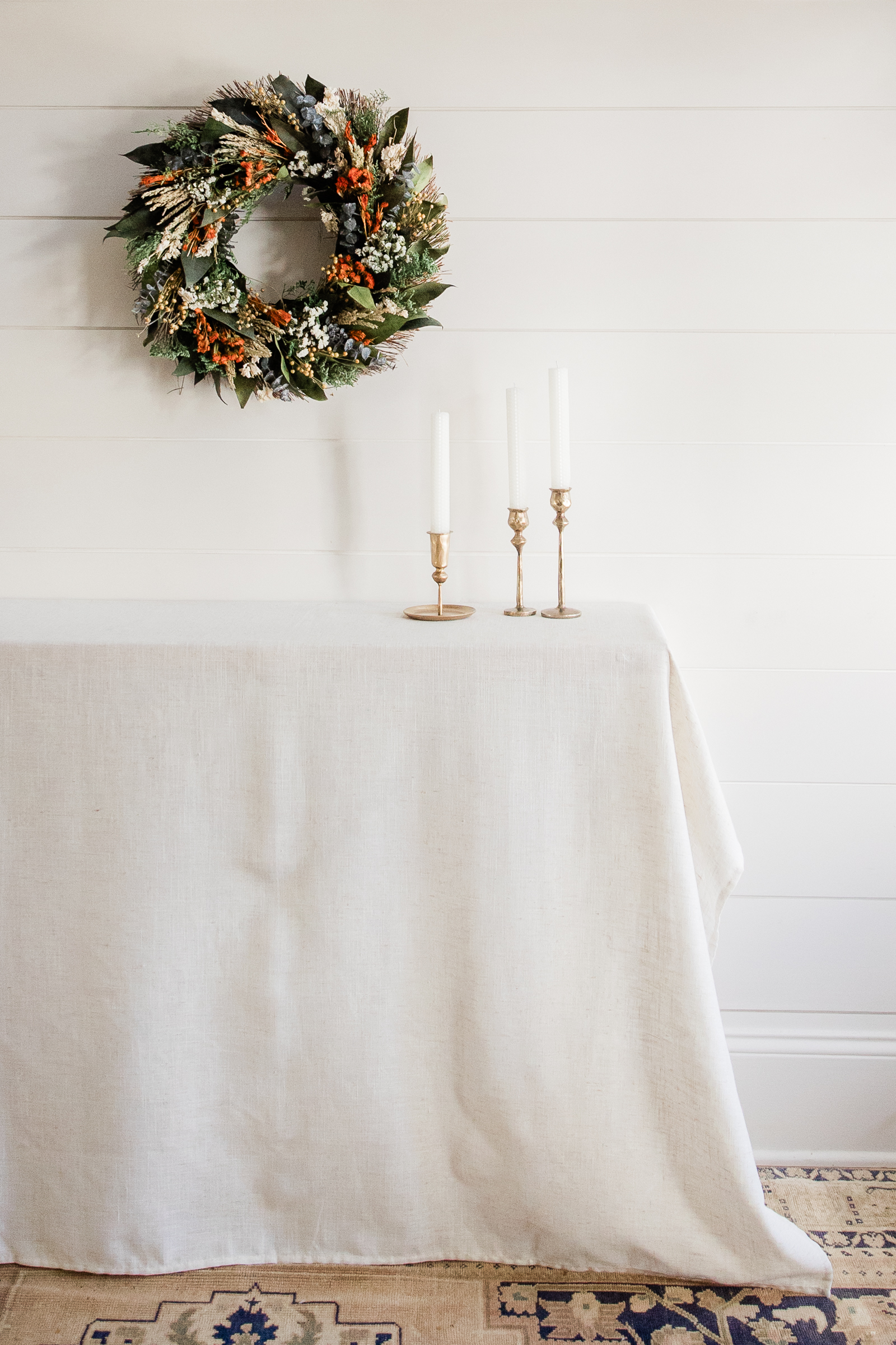 Fall wreath and brass candlesticks styled on a neutral table for ecommerce branding product photography.