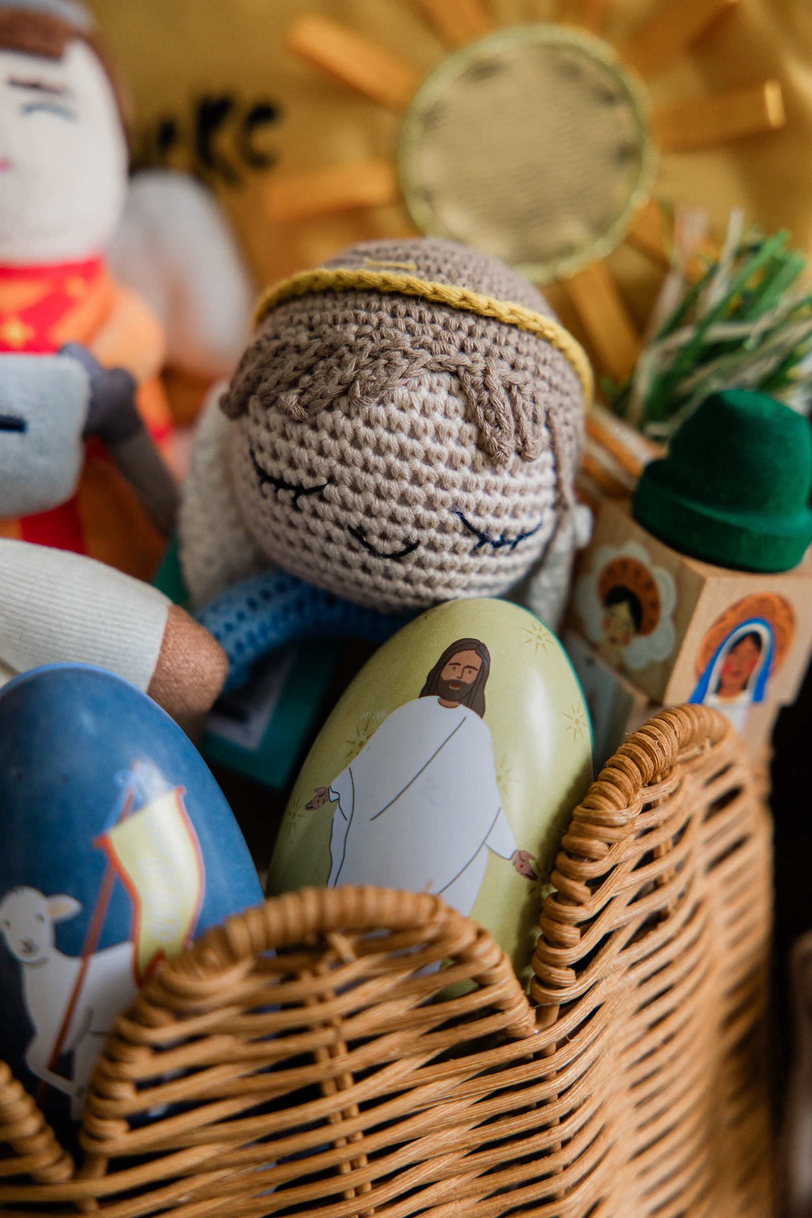 Catholic children’s toys and devotional items arranged in a basket for online shop product photography.
