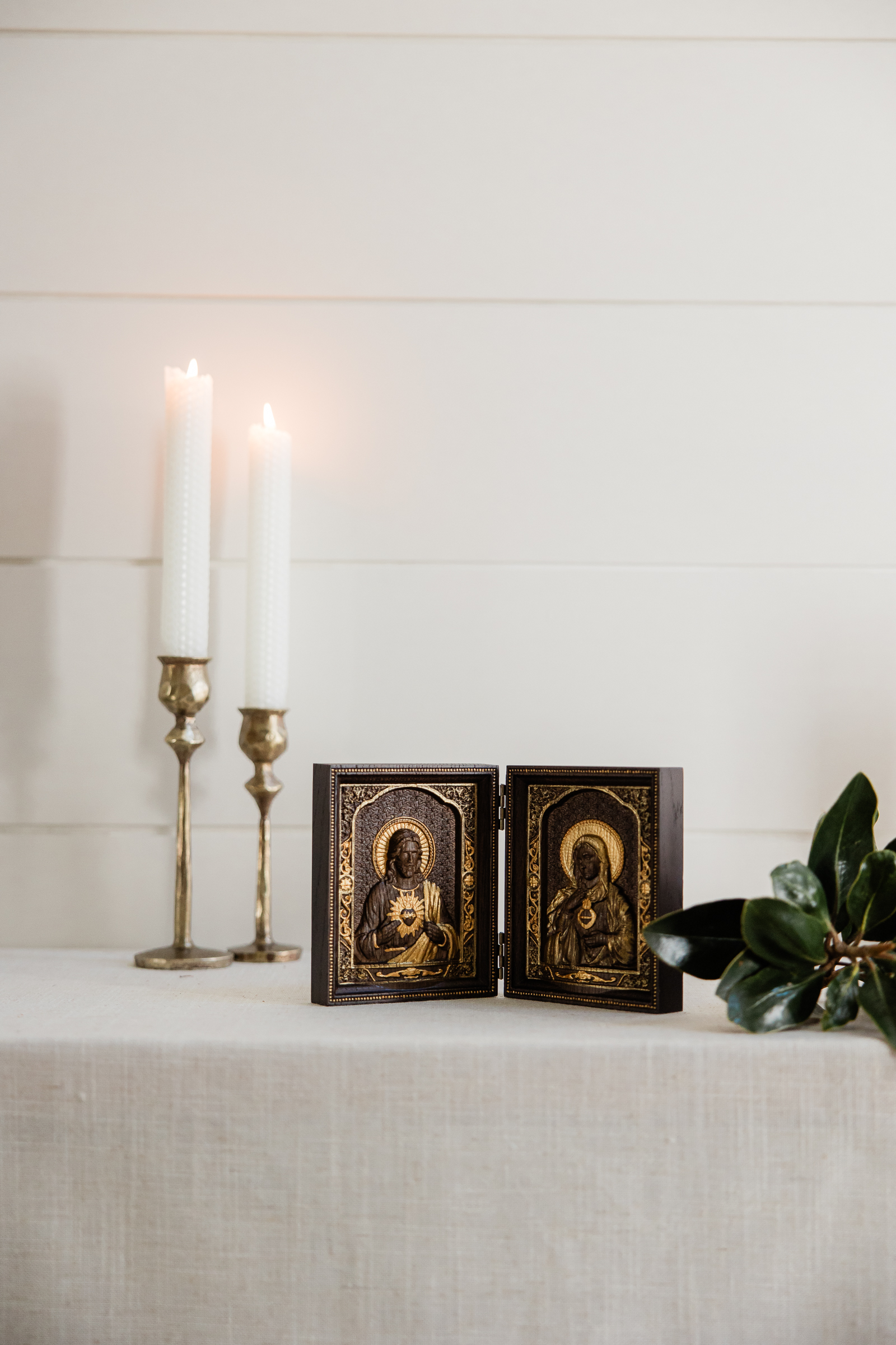 Catholic home altar with brass candlesticks and sacred heart icon styled for ecommerce branding photography.