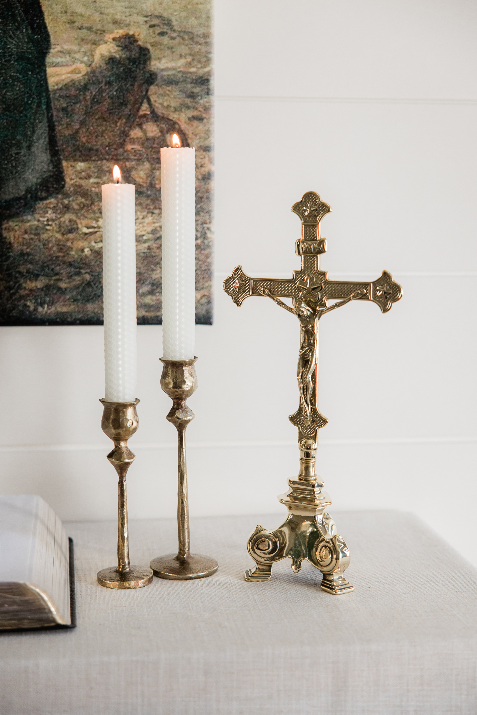 Catholic crucifix and candlesticks styled on a neutral tabletop for ecommerce branding imagery.