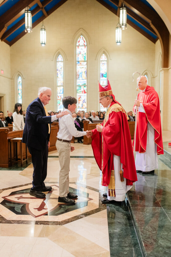A young man greeted by the bishop and clergy during a parish sacrament, photographed by a Catholic photographer