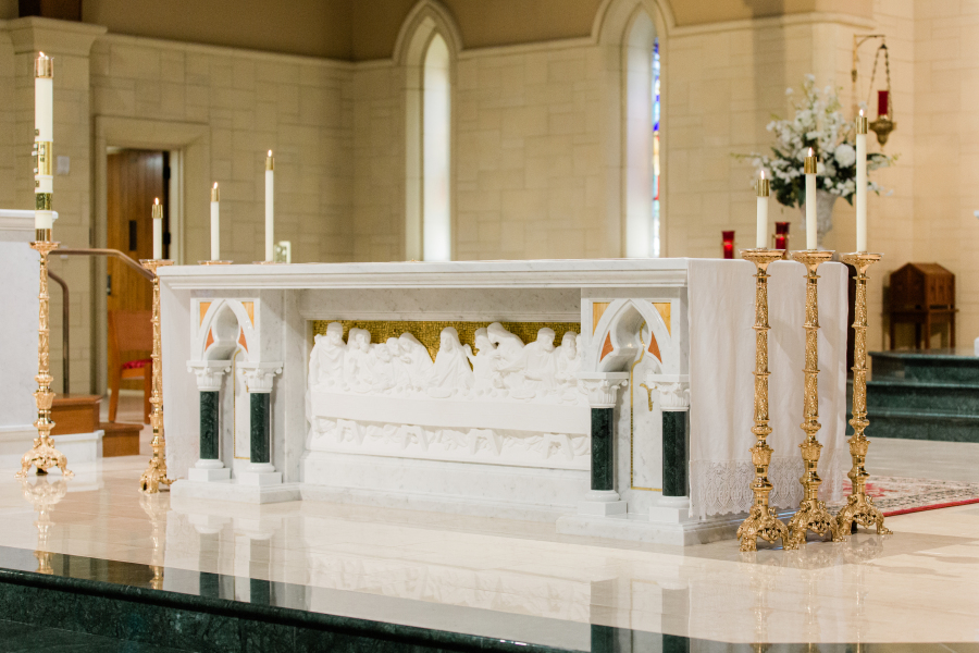 White marble altar decorated with candles and flowers, photographed by a Catholic photographer