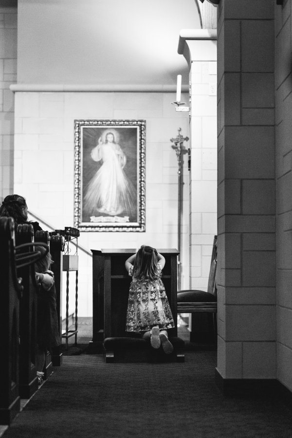 A young girl kneeling in prayer before a Divine Mercy image, photographed by a Catholic photographer