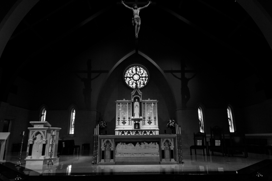 Black and white close-up of a crucifix and church window, photographed by a Catholic photographer